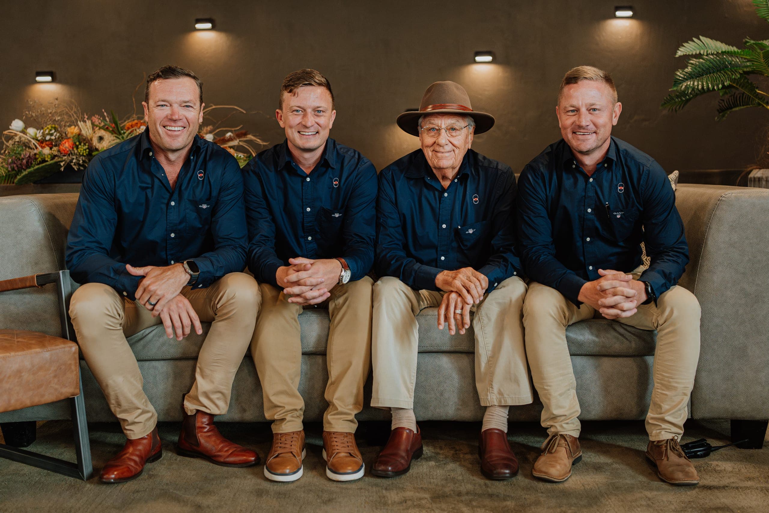 Four men in navy shirts on a couch at a Platinum Auction